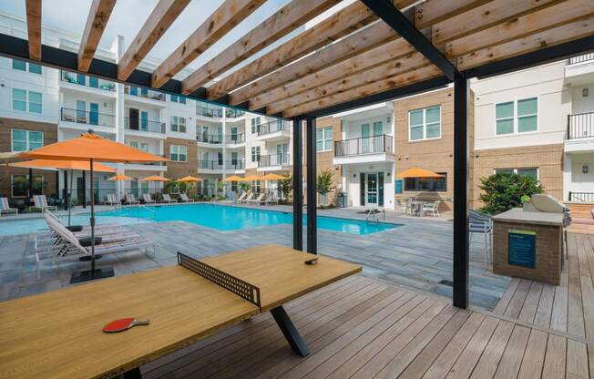 a swimming pool with a picnic table in front of an apartment building