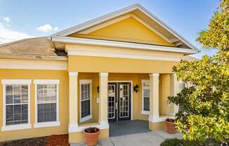 A yellow house with a brown roof and a glass door.