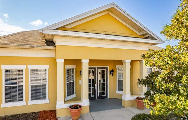 A yellow house with a brown roof and a glass door.