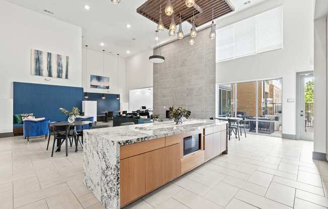 A modern kitchen with a marble island and pendant lights.