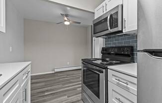 a kitchen with white cabinets and black appliances and a ceiling fan