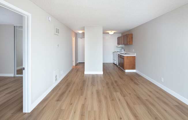 a spacious living room with hardwood flooring and an open kitchen