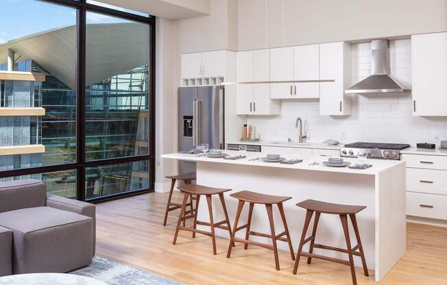A kitchen with white cabinets and a large island with bar stools.