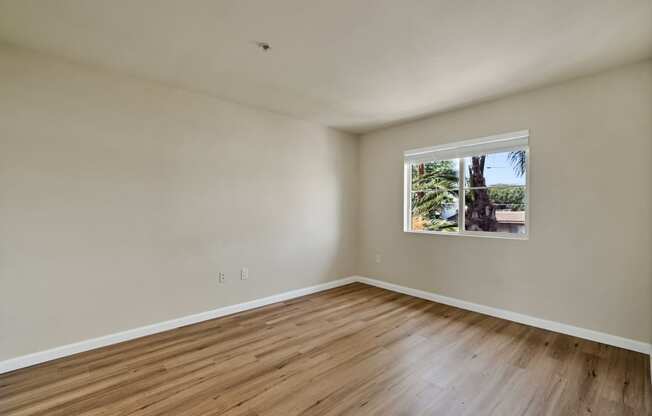 an empty room with wood floors and a window