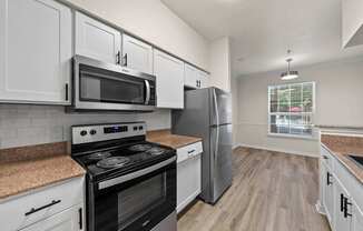 A kitchen with a stove, microwave, and refrigerator.
