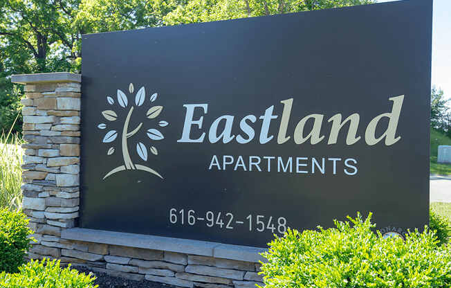 a stone monument sign for eastland apartments with trees in the background