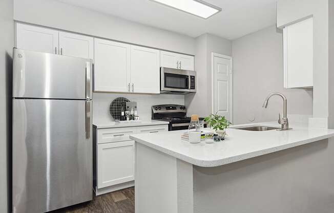 Model Kitchen with White Cabinets and Wood-Style Flooring at Grand Pavilion Apartments in Tampa, FL.