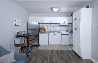 Apartments for Rent Haltom City TX - Desert Sands - Kitchen with Hardwood-Inspired Flooring, Tiled Backsplash, White Cabinets, and Dining Area