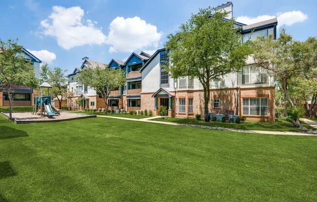 A large grassy area in front of a building with a playground.