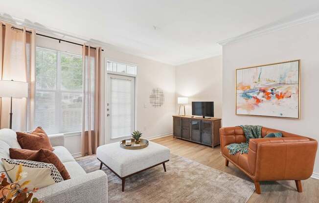 A living room with a grey sofa, a white coffee table, a brown leather chair, and a painting on the wall.