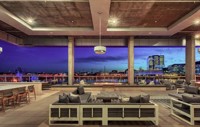 A modern outdoor seating area with a view of the city skyline at dusk.