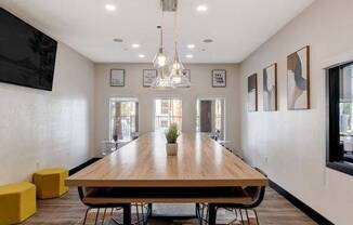 A modern dining room with a long wooden table and yellow stools.