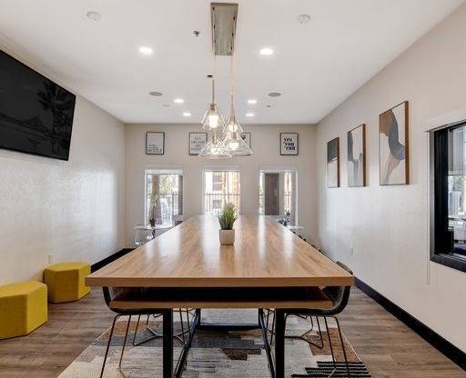 A modern dining room with a long wooden table and yellow stools.