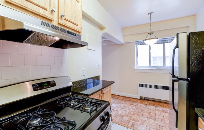 kitchen with wood cabinetry, gas range, and stainless steel appliances sherry hall apartments in washington dc
