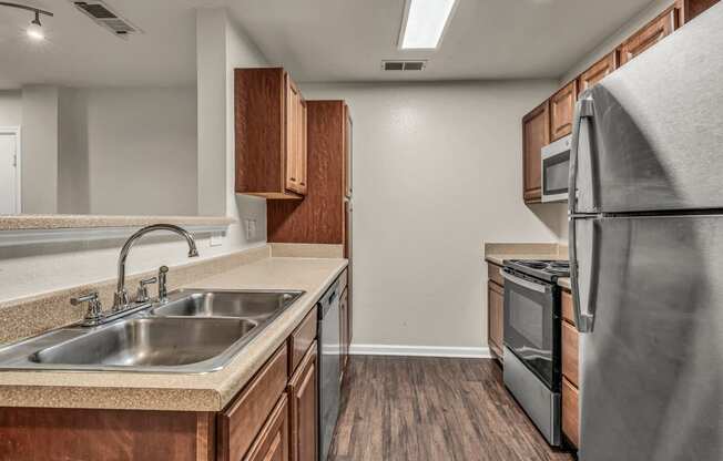 an empty kitchen with stainless steel appliances and wooden cabinets
