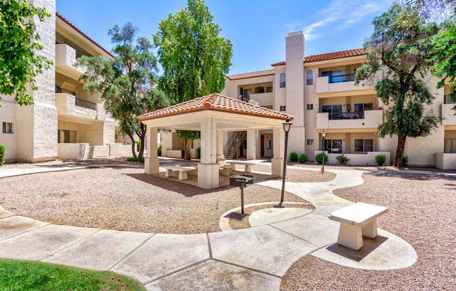 A courtyard with a pavilion and benches surrounded by buildings.