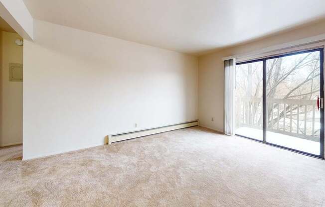 A living room with a carpeted floor and a sliding glass door to a balcony at Waverly Park Apartments, Lansing