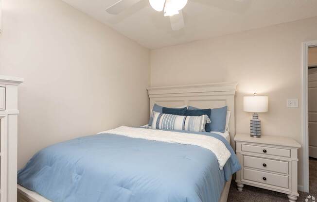 A bedroom with a bed, nightstand, and ceiling fan.