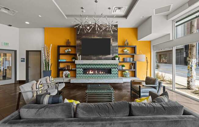 A living room with a grey sofa and a television on a yellow wall.
