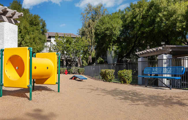 a playground with yellow and blue playground equipment and a blue bench