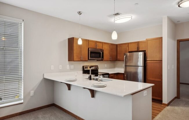 the view of a kitchen with a large island and a stainless steel refrigerator