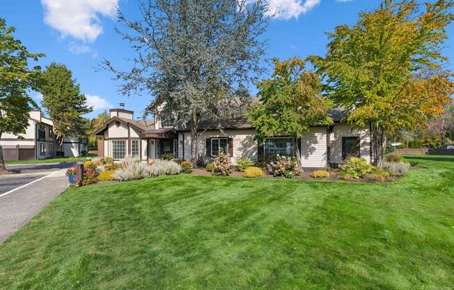 A house with a green lawn and trees in front.