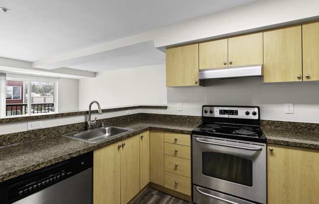 a kitchen with granite-look countertops. wood-look cabinets, and stainless steel appliances at Arabella Apartment Homes, Shoreline, WA