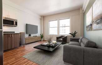 A modern living room with a grey sofa, a coffee table, and a television. at Addison on Fourth Apartments, Washington