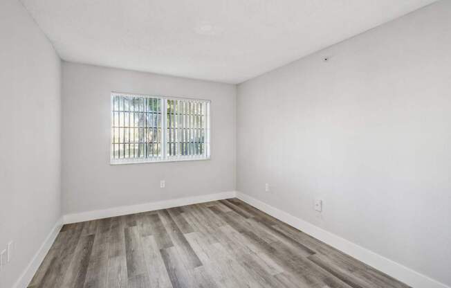 A room with a window and wooden flooring.