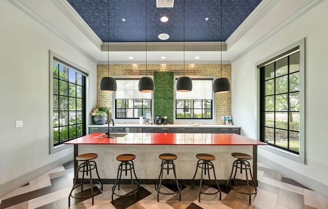 a kitchen with an island and stools in front of windows
