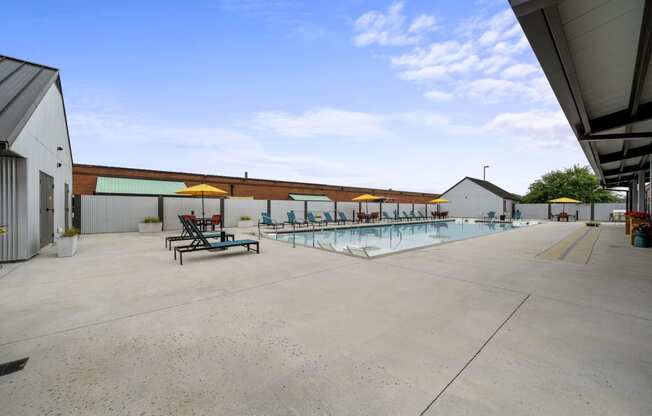 a large pool with lounge chairs and umbrellas in front of a building