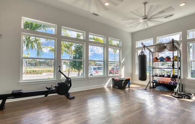 A spacious room with a treadmill, a punching bag, and a rack of exercise equipment.