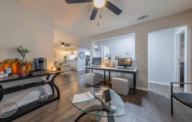 a living room with a ceiling fan and a desk with a computer