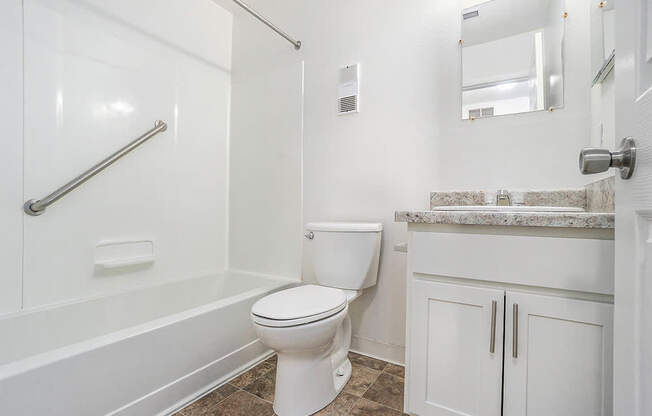 A white toilet in a bathroom with a marble counter.