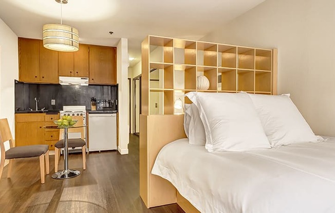 a bedroom with a bed and a kitchen in the background