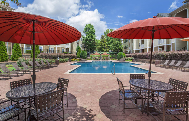 a swimming pool with umbrellas and tables with chairs