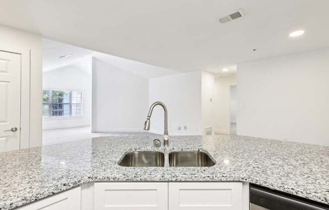 A kitchen with a granite countertop and a stainless steel sink.