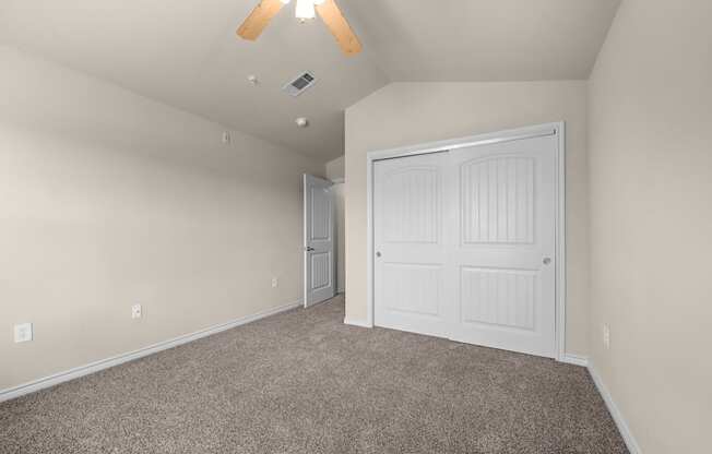 A room with a white door and a ceiling fan.