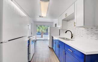 A kitchen with white appliances and blue cabinets.