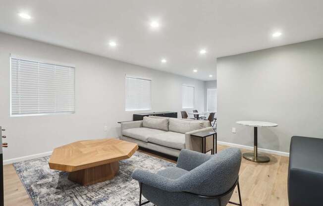 A modern living room with a grey sofa, a wooden coffee table, and a grey armchair.