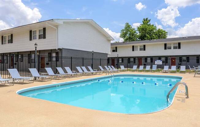 A large swimming pool with lounge chairs in front of a white building at Spring Creek Townhomes Apartments, Springfield, Illinois