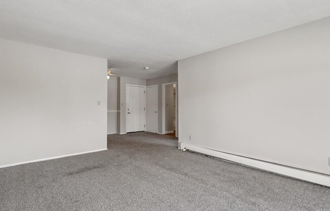 an empty living room with white walls and carpet