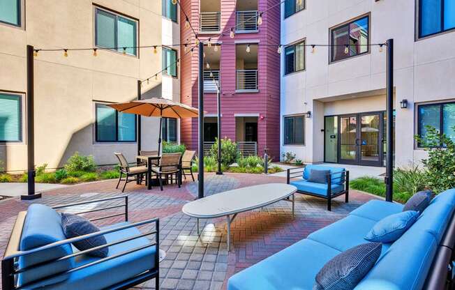 A patio with a blue couch and a table with chairs.