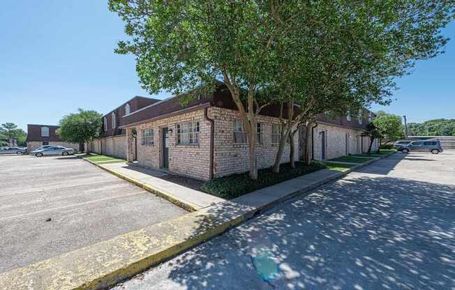 A parking lot with a building and a tree in front.