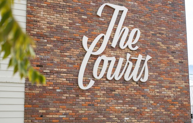 a brick wall with a white sign on it at The Courts Midtown, Memphis, TN, 38104