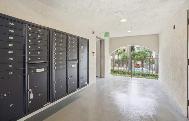 A hallway with a row of lockers on the left and a doorway leading to a balcony on the right.
