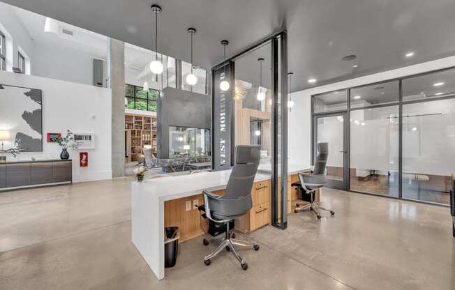 the kitchen has a large island with three chairs and a glass walled office area