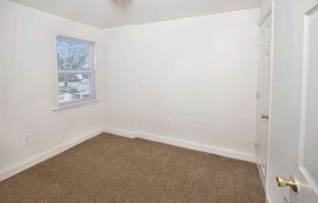 A room with a carpeted floor and a door on the right side.