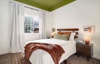 A bedroom with a bed, nightstand, and window.