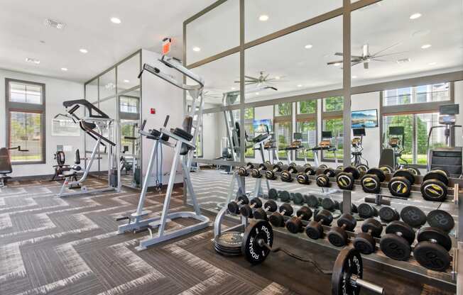 a gym with weights and a large glass walled room with windows